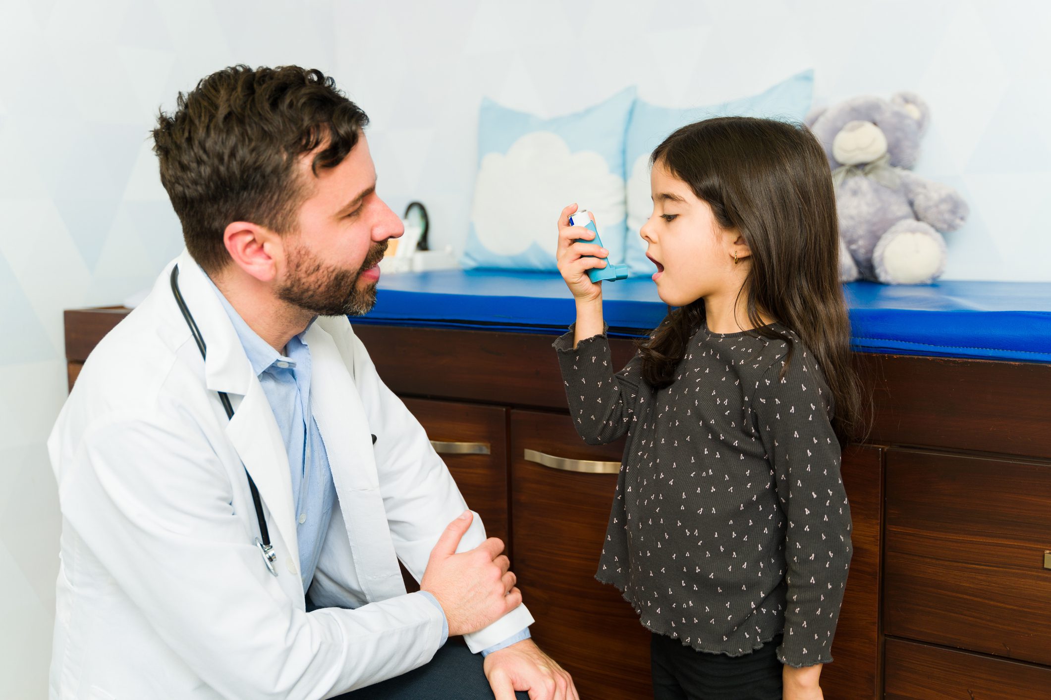 Adorable young kid having trouble breathing using an asthma inhaler at the doctor's office